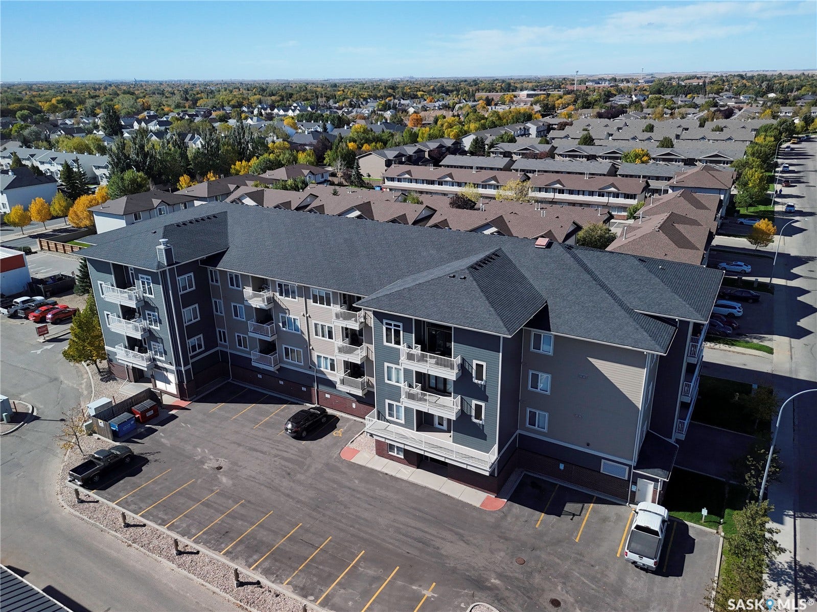 Multi-story residential building with private balconies and surface parking