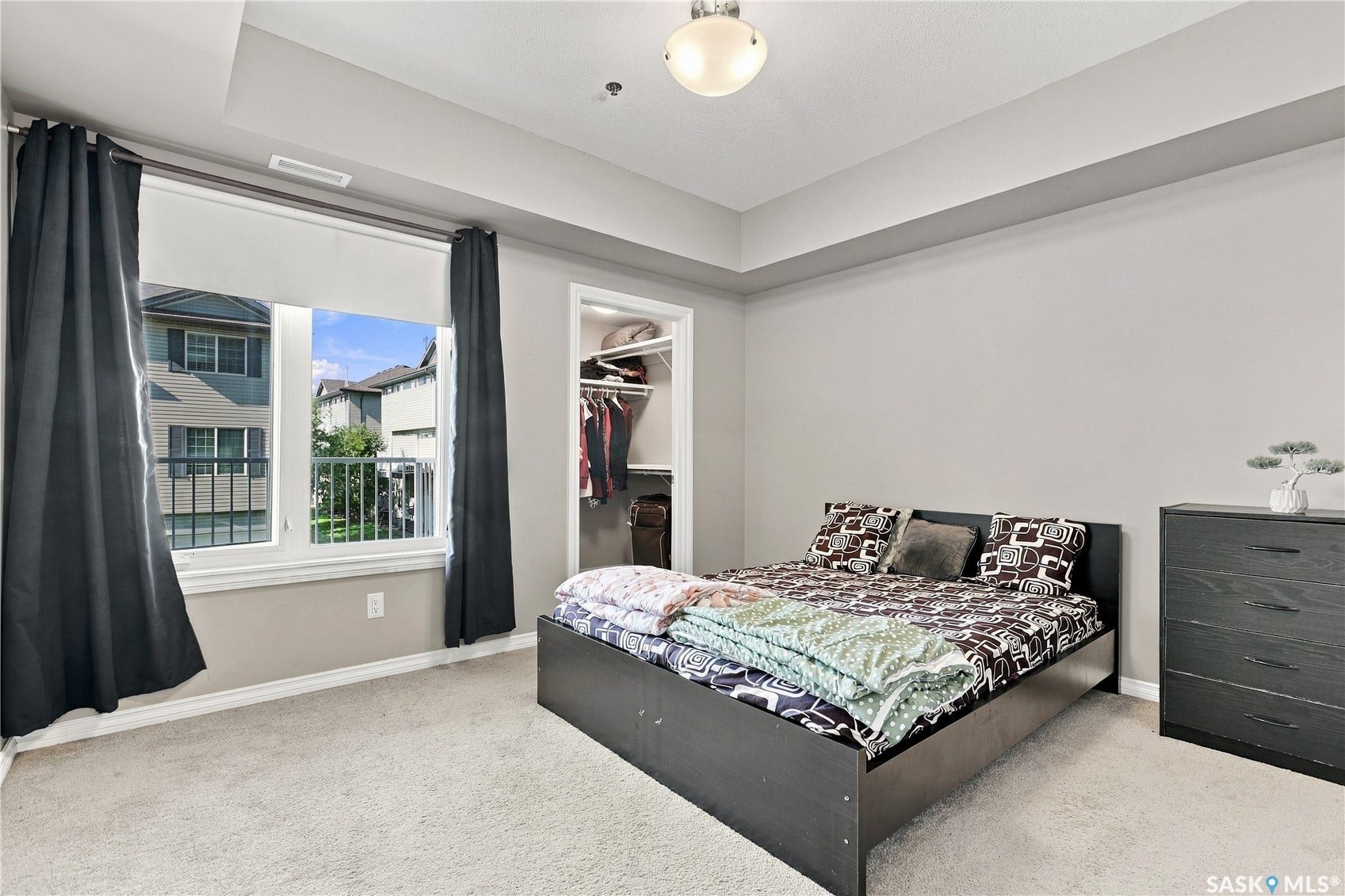 Carpeted flooring, recessed ceiling, large window with roller shade, and an open closet featuring built-in shelving