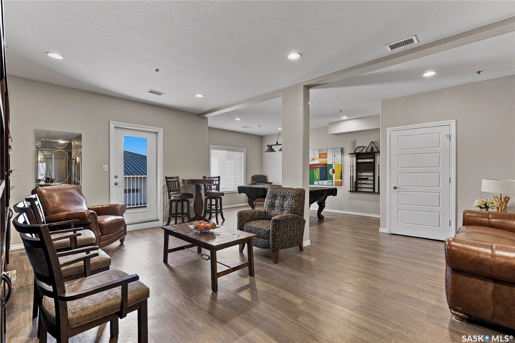 Spacious open-concept room featuring wood-finish flooring, recessed lighting, and a paneled door