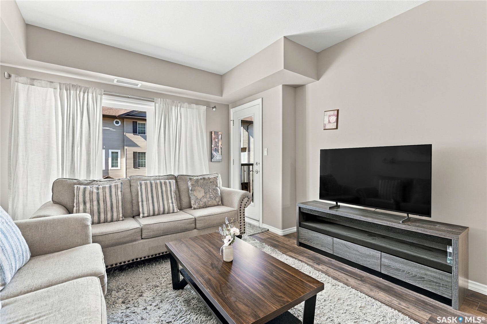 Open living space featuring light-toned walls, wood-finish flooring, and a sliding glass door