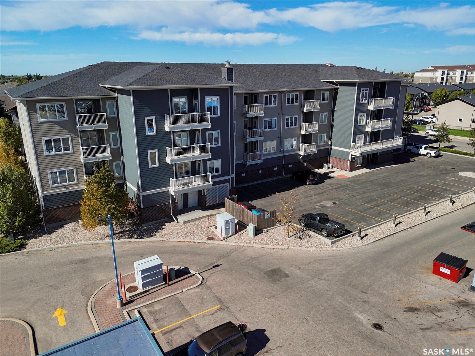 Multi-story residential building with a dark shingle roof and balconies
