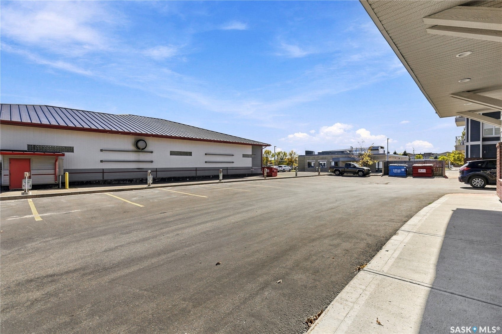 Paved parking area with marked spaces and building featuring a metal roof