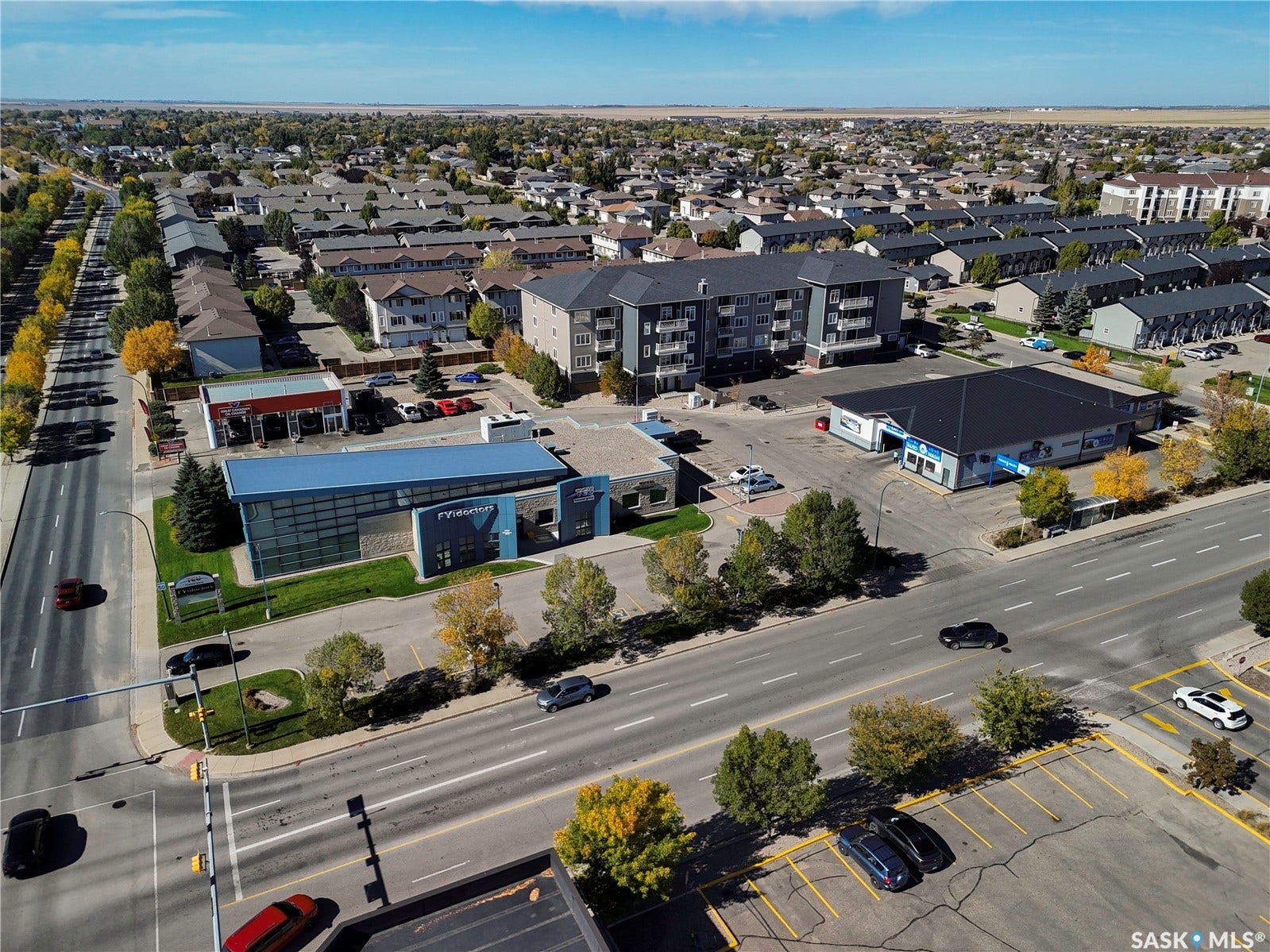 Aerial perspective showcasing a mixed-use neighborhood with commercial buildings, multi-story residential structures, and single-family homes