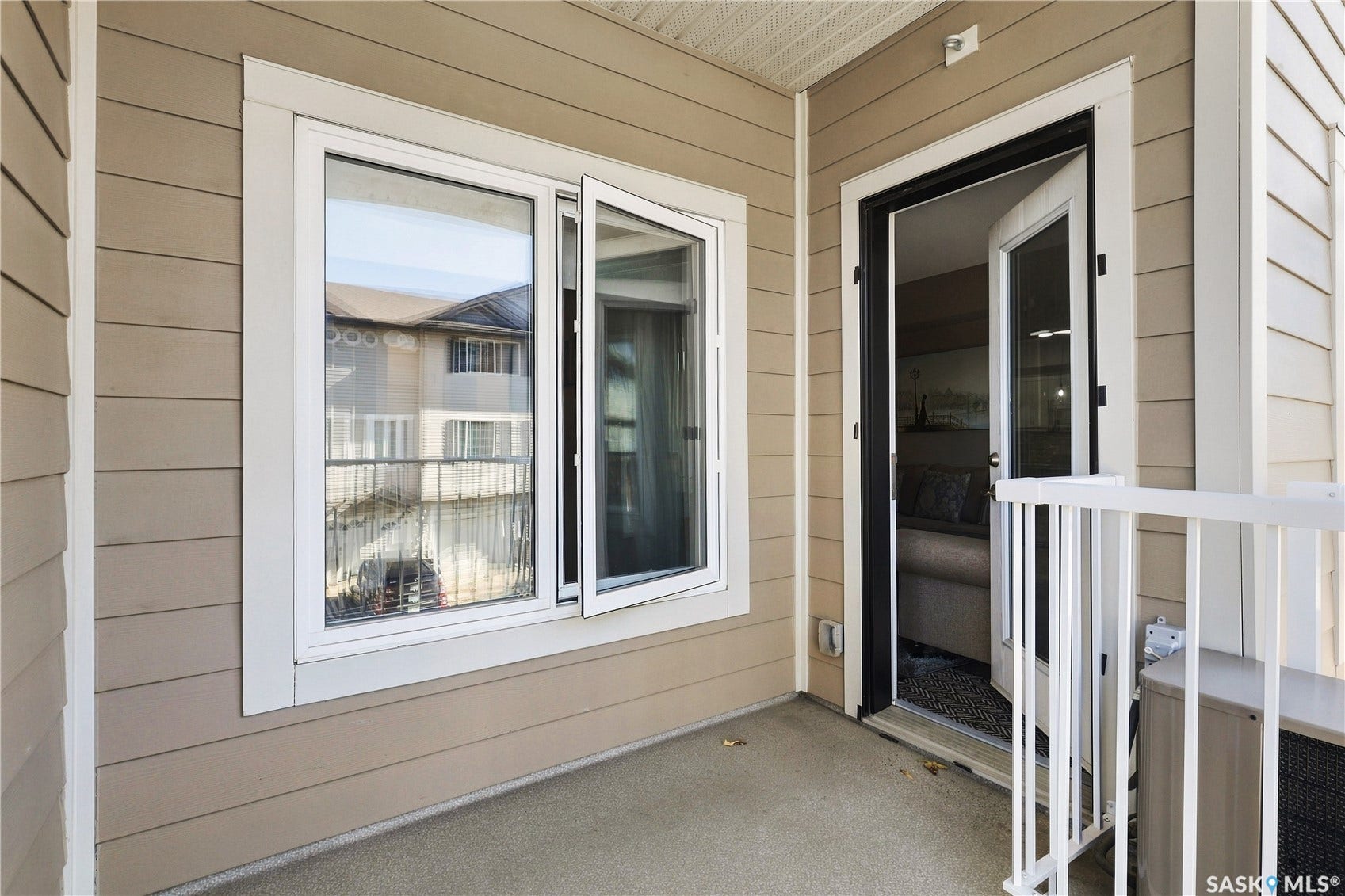 Patio entry featuring durable siding, white-framed window, and a white-framed glass door