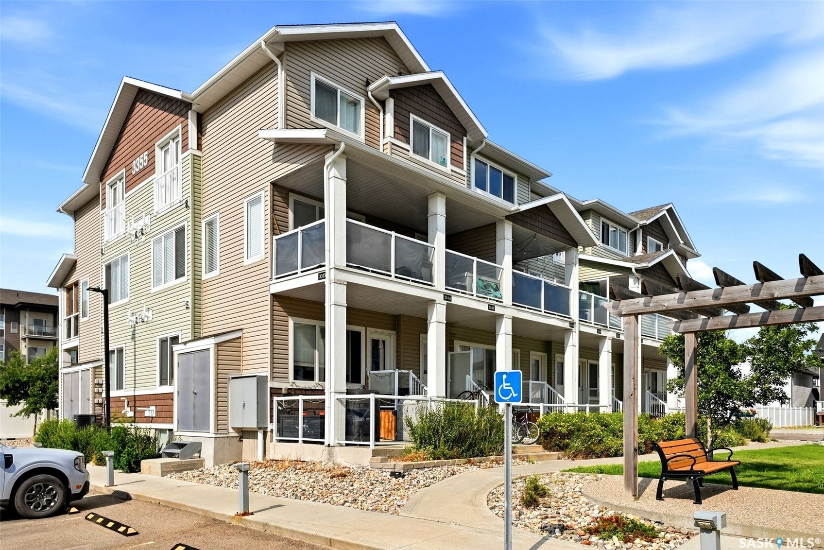 Multi-level townhome exterior featuring varied siding materials, multiple balconies with glass railings, and peaked rooflines
