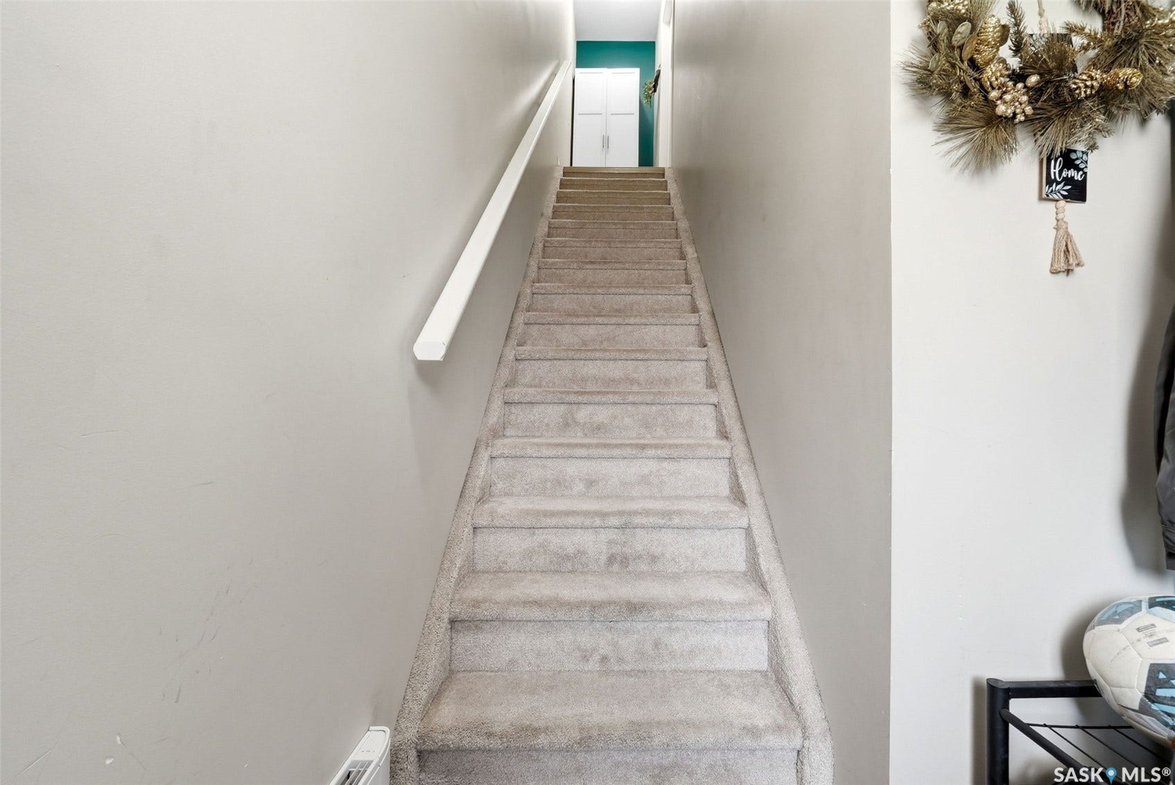Carpeted staircase with a white handrail, leading to a landing with a teal accent wall