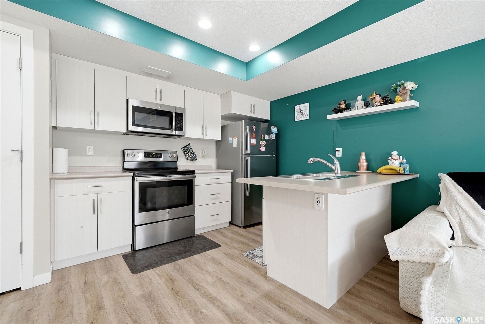Kitchen featuring stainless steel appliances, white cabinetry, wood-finish flooring, and recessed ceiling lighting