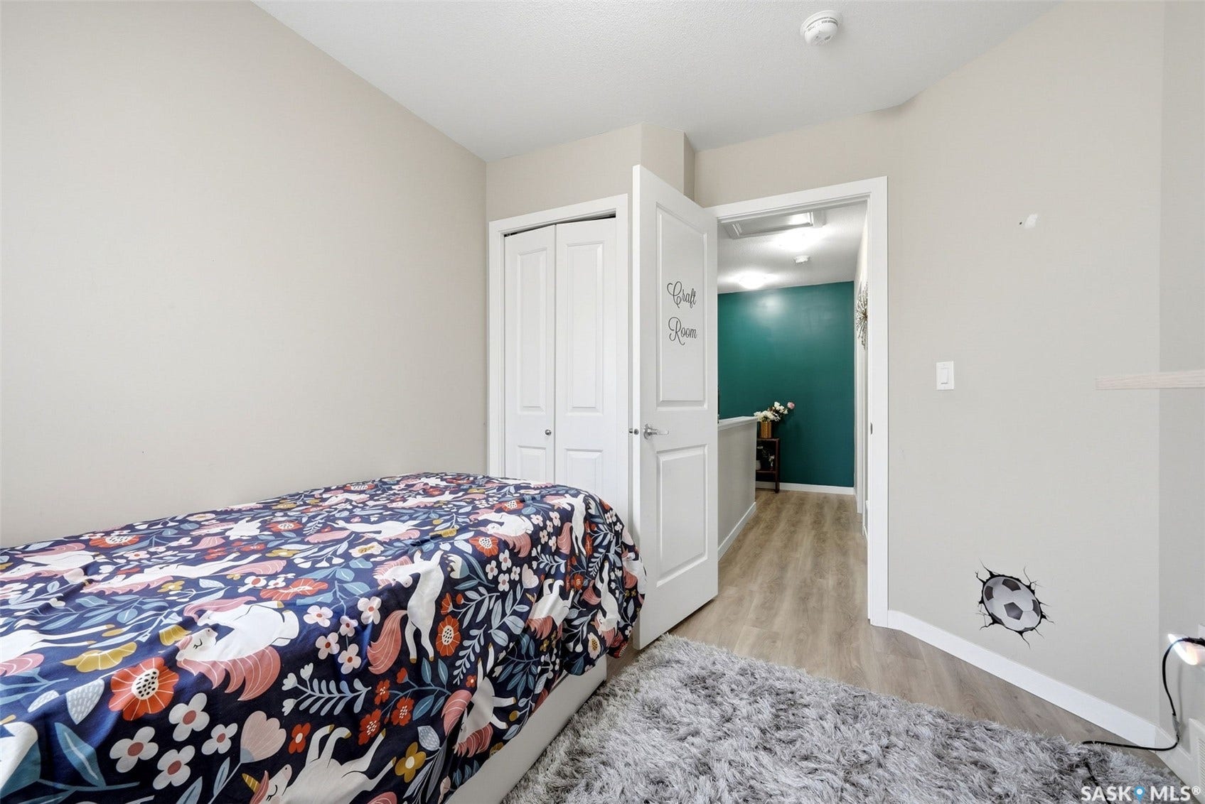 Light neutral wall color, overhead lighting, white bi-fold closet doors, wood-finish flooring in the hallway, and a white interior door