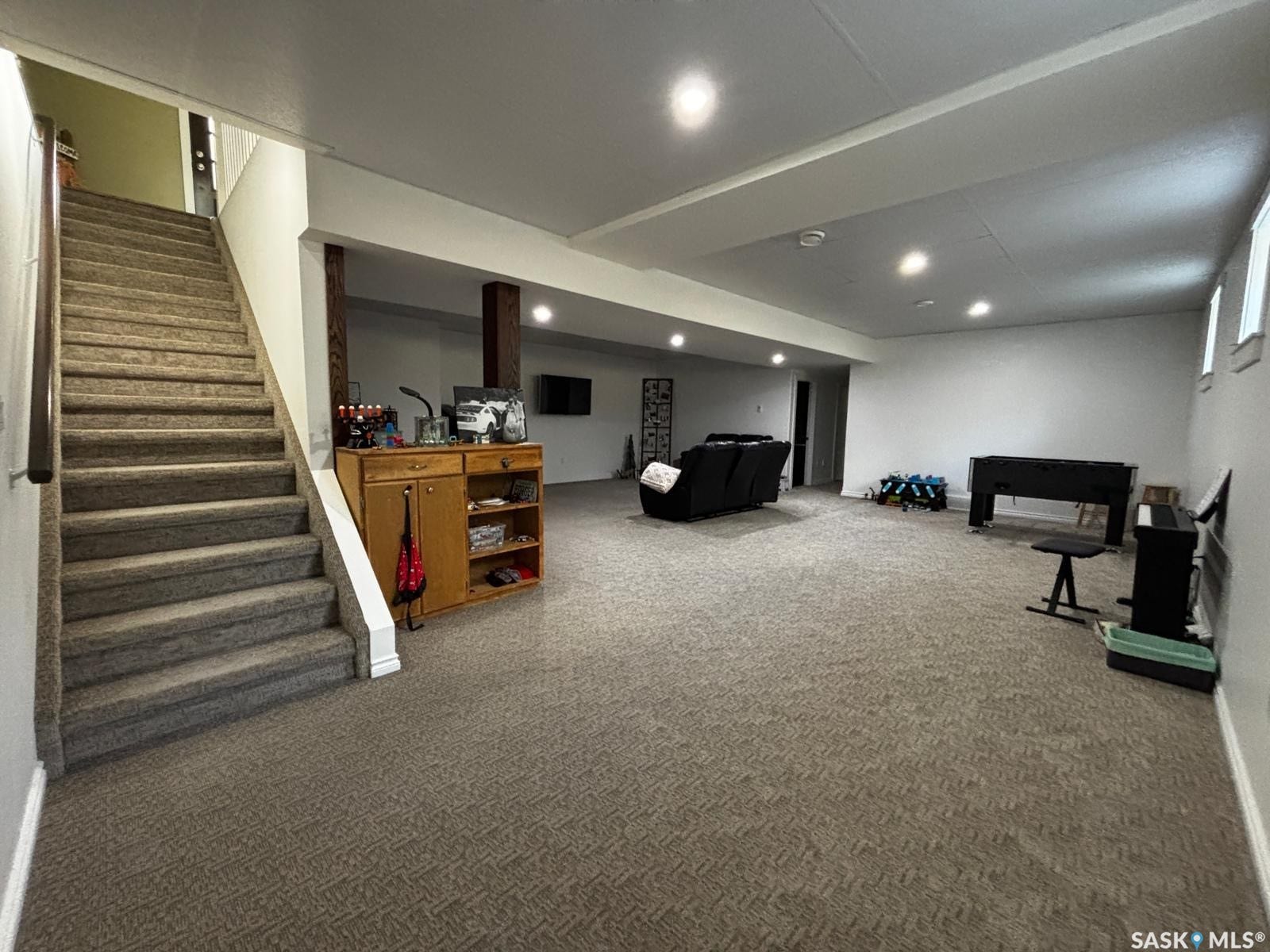 Expansive lower-level space featuring recessed lighting, carpeting, three windows, and structural wood support beams