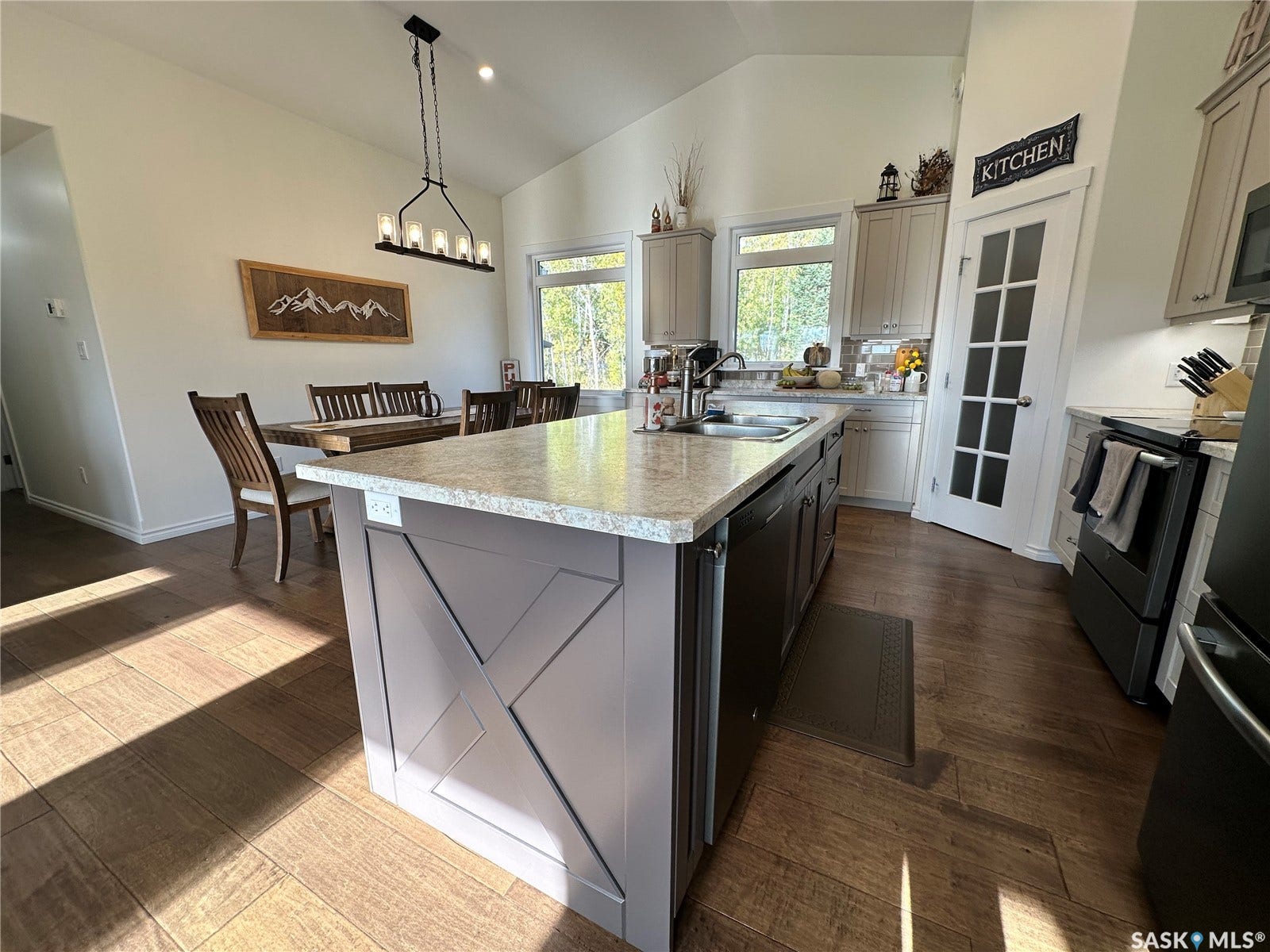 Spacious kitchen featuring a large island with a stone-finish countertop, wood-finish flooring, vaulted ceilings, and recessed lighting