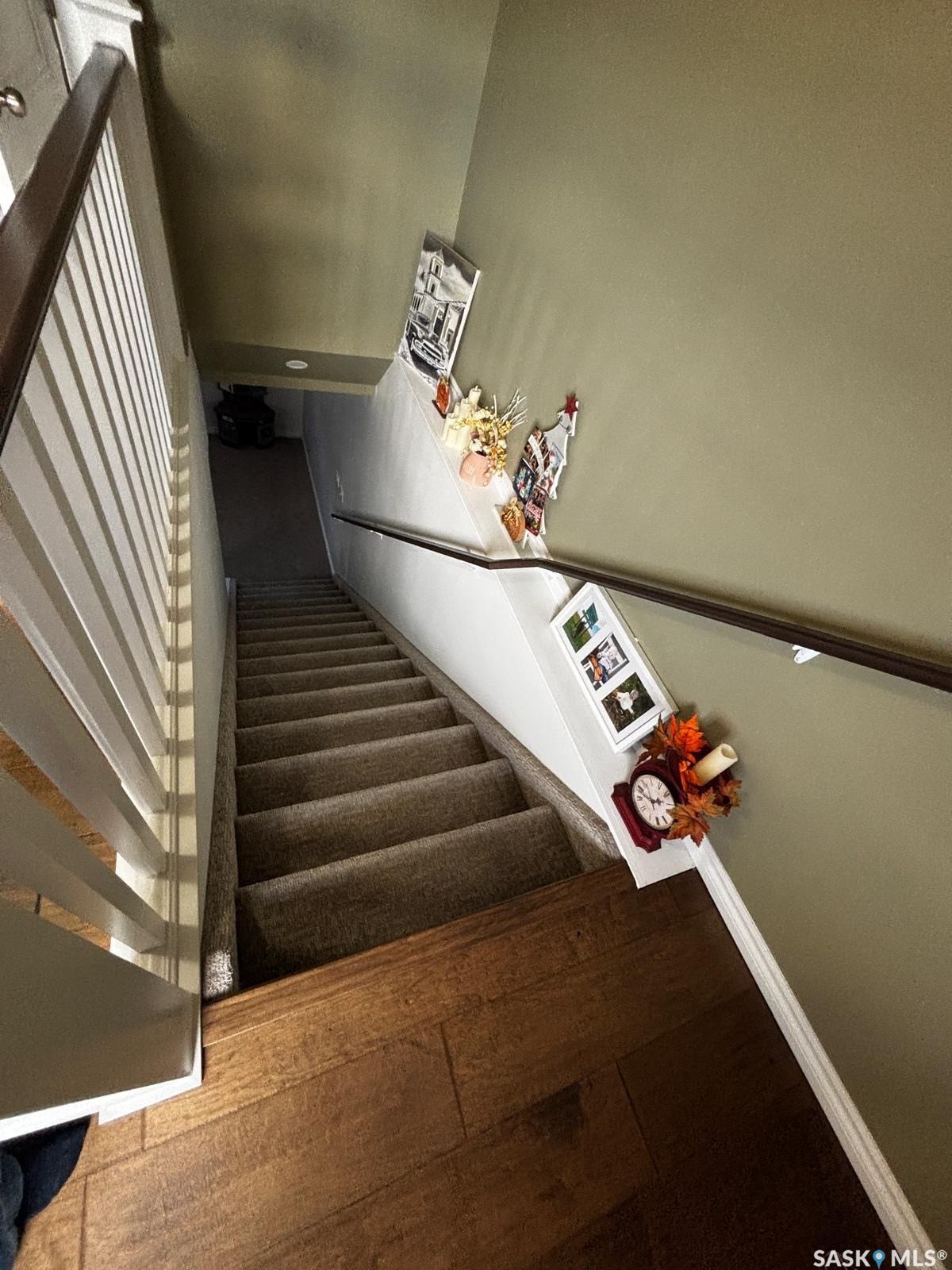 Carpeted staircase with a wood-finish handrail and painted balusters