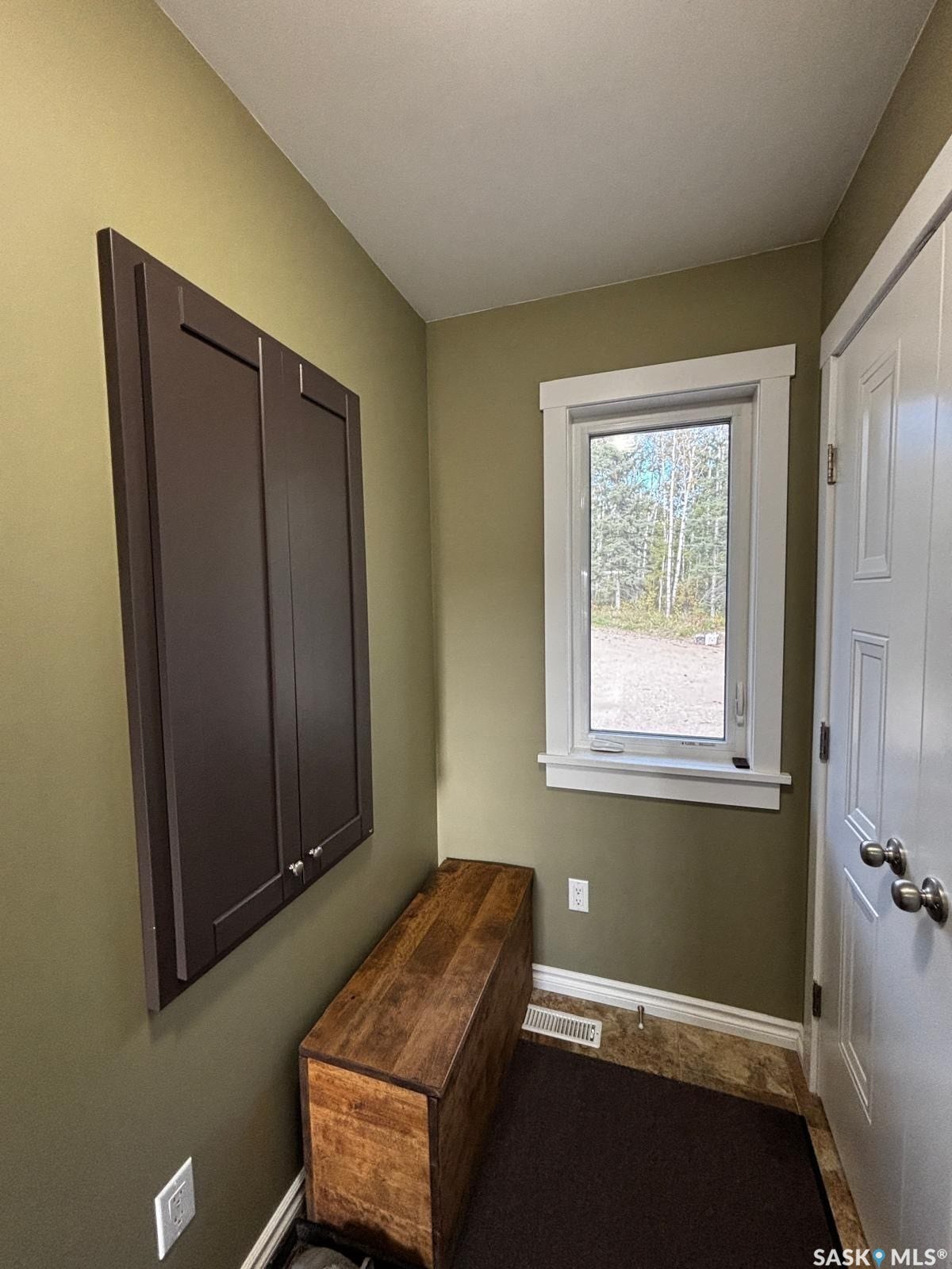 Built-in wall cabinetry, single window with white trim, white paneled door with brushed nickel hardware, and marble-finish flooring