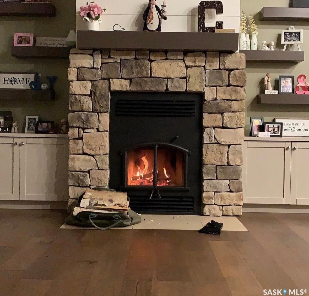 Wood burning, Stone-clad fireplace with a dark wood mantel. Imagine, how cozy it would be hearing the birch crackle watching this fire in the middle of winter.