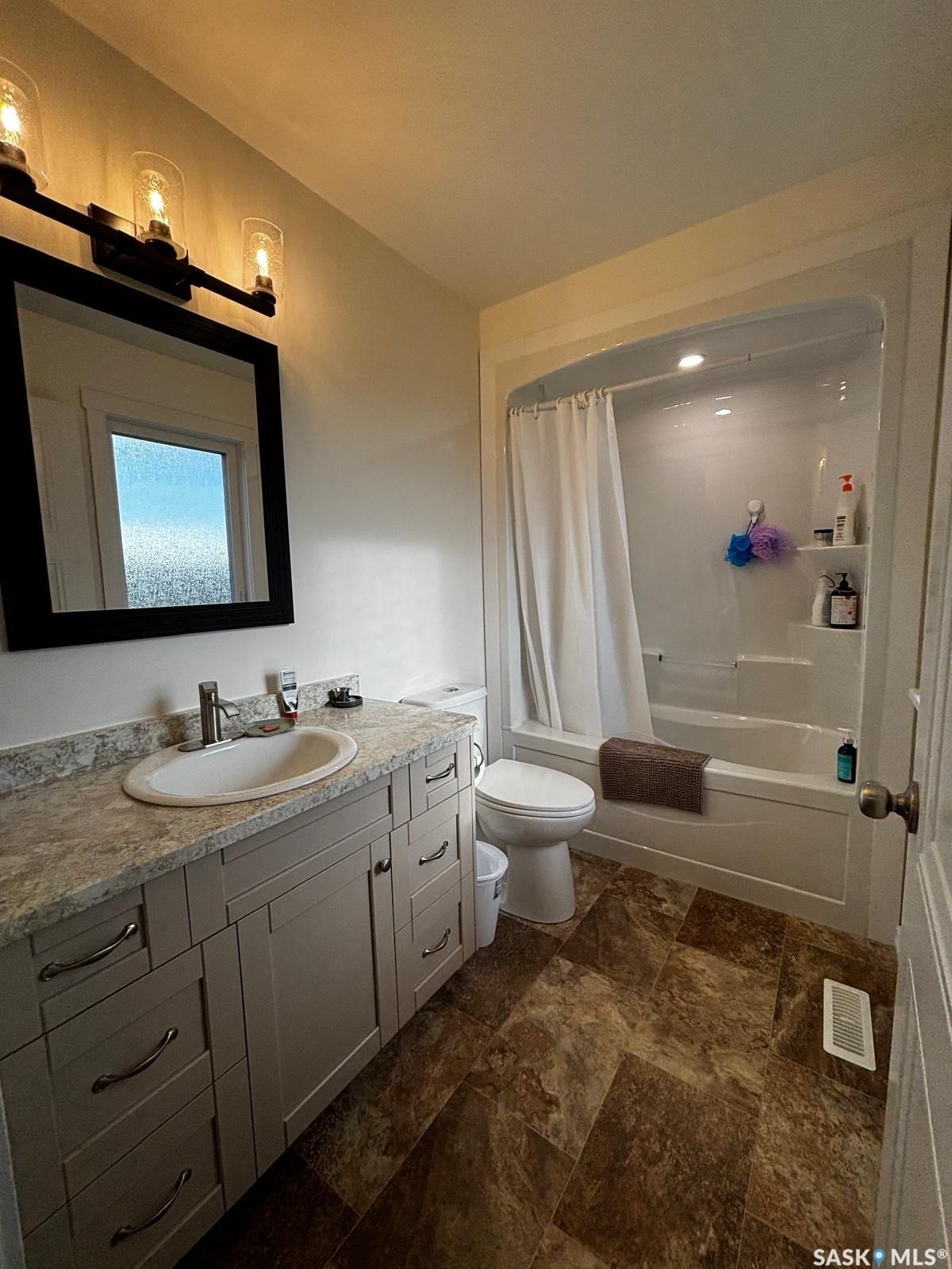 Recessed lighting illuminates the white bathtub and shower surround