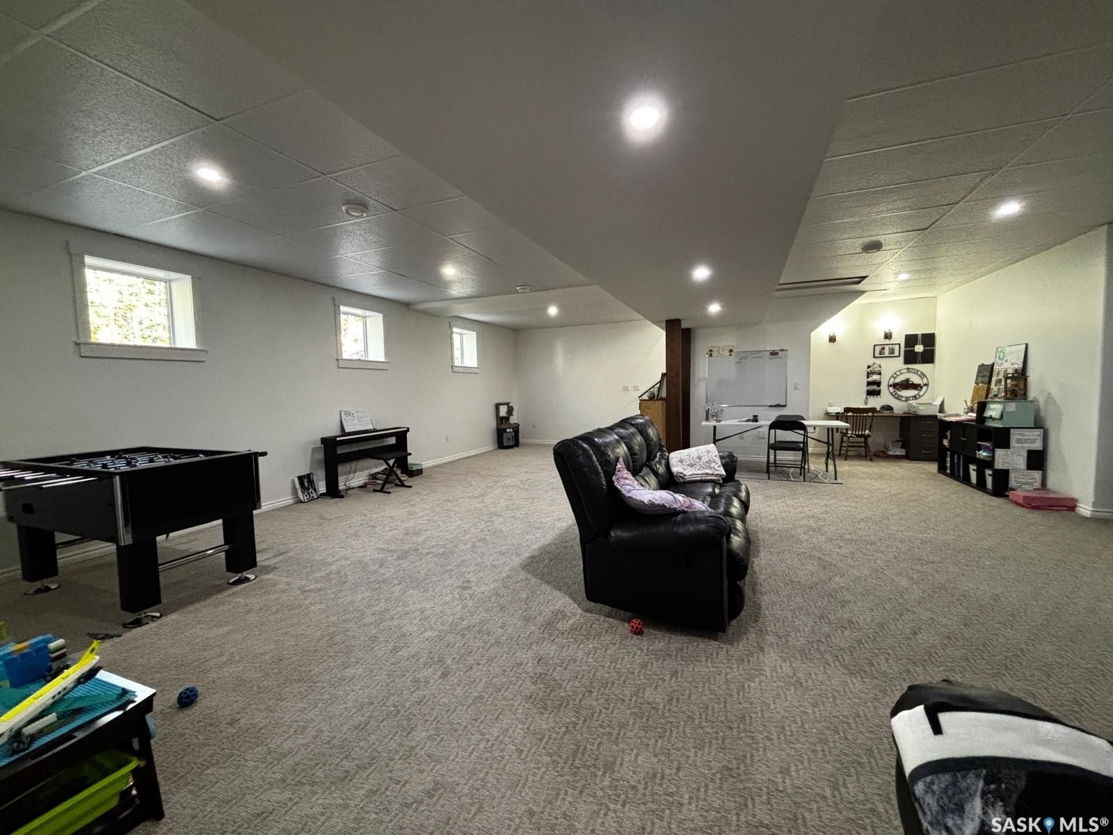 Recessed lighting, drop ceiling, light neutral-toned carpeting, wood structural column, and multiple windows