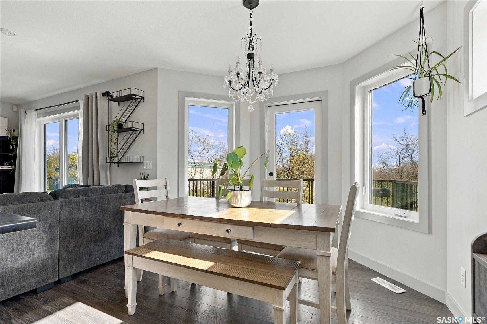 Dining area featuring laminate flooring, a chandelier, and multiple windows overlooking the balcony
