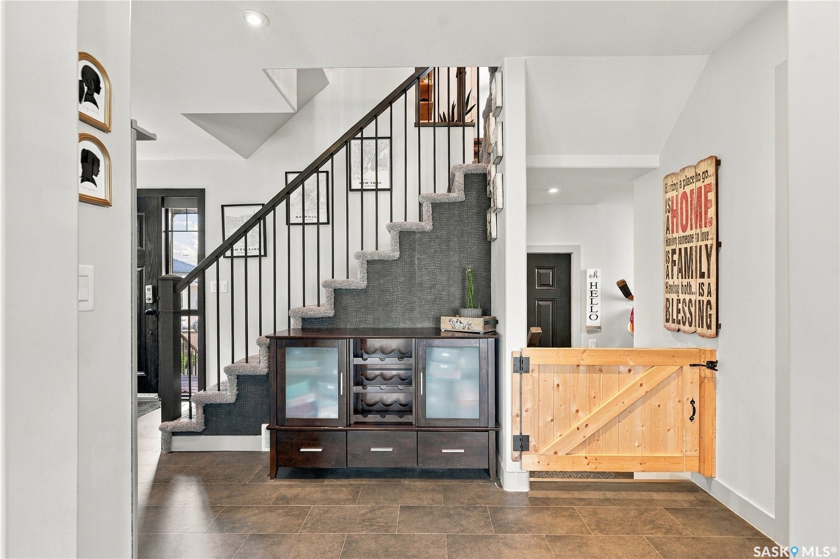 Staircase featuring carpeted treads, dark wood handrail, and wrought iron balusters
