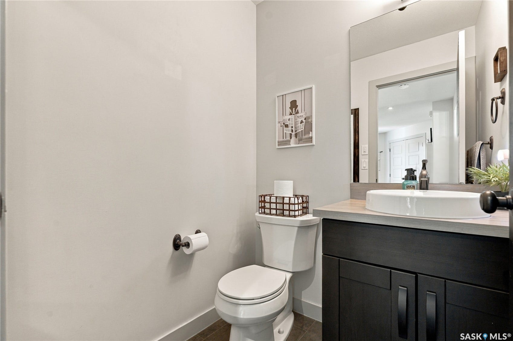 Main floor powder room featuring a sleek vanity with a vessel sink, a large wall mirror, and modern cabinetry