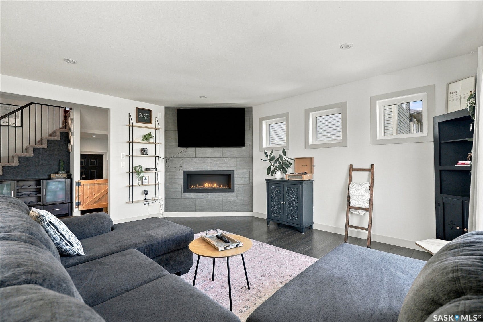 Living room with plenty of natural light, a gas fireplace and dark laminate flooring