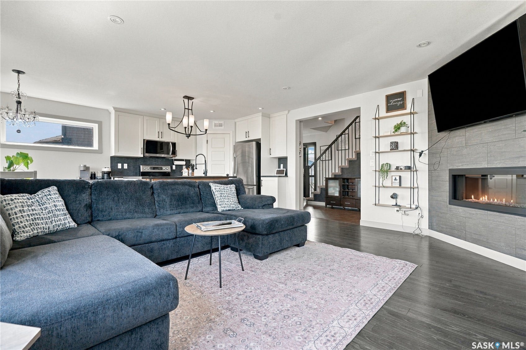 Open-concept living space featuring laminate flooring and a gas fireplace with a tiled surround