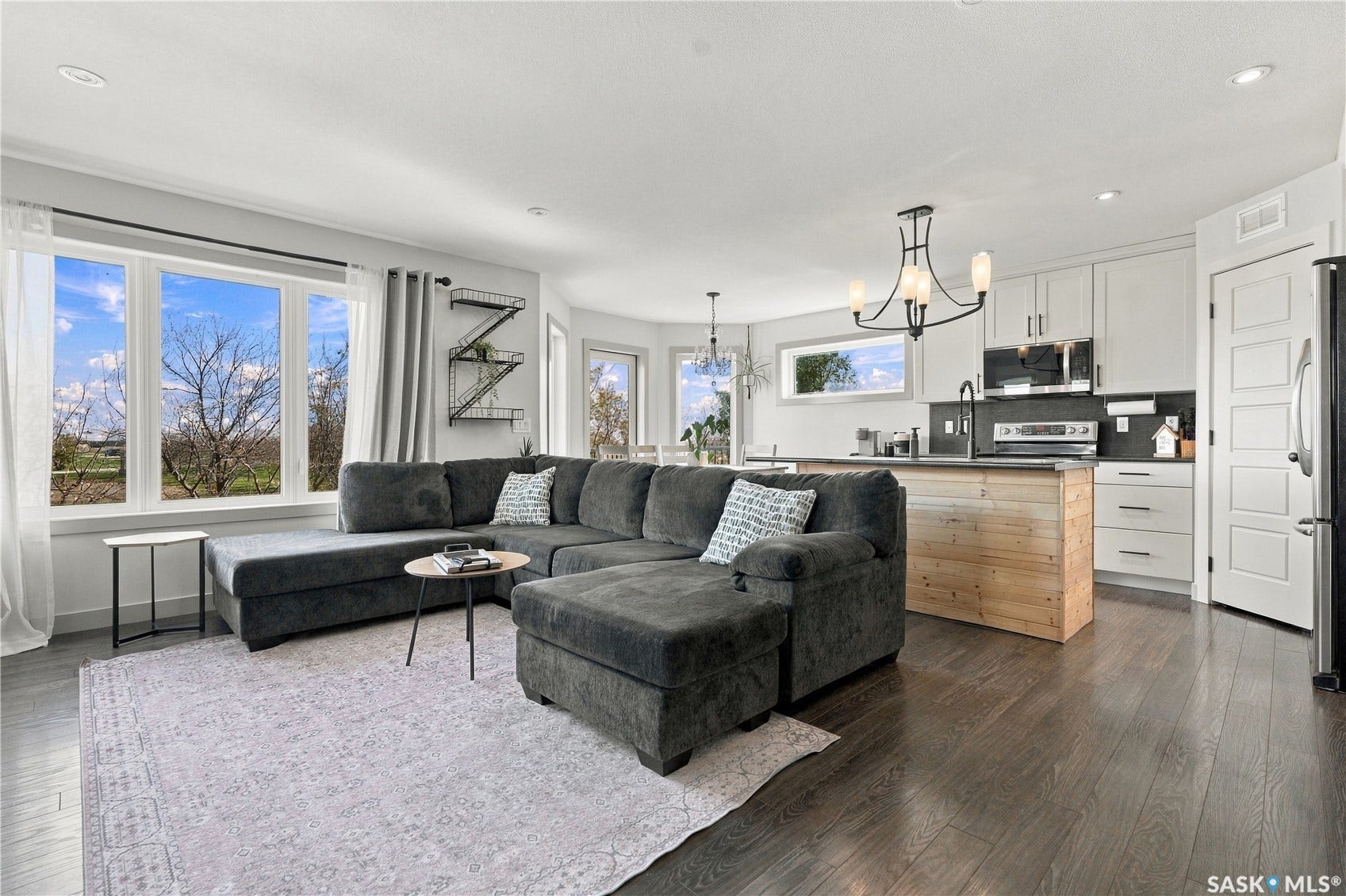 Open-concept living space with dark laminate flooring, white walls, and recessed lighting