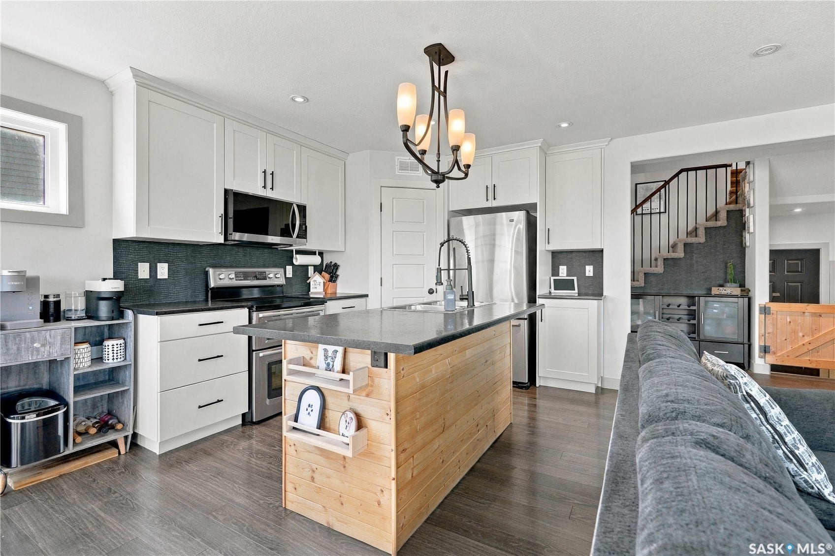 Kitchen featuring white shaker cabinetry, stainless steel appliances, a center island and laminate flooring