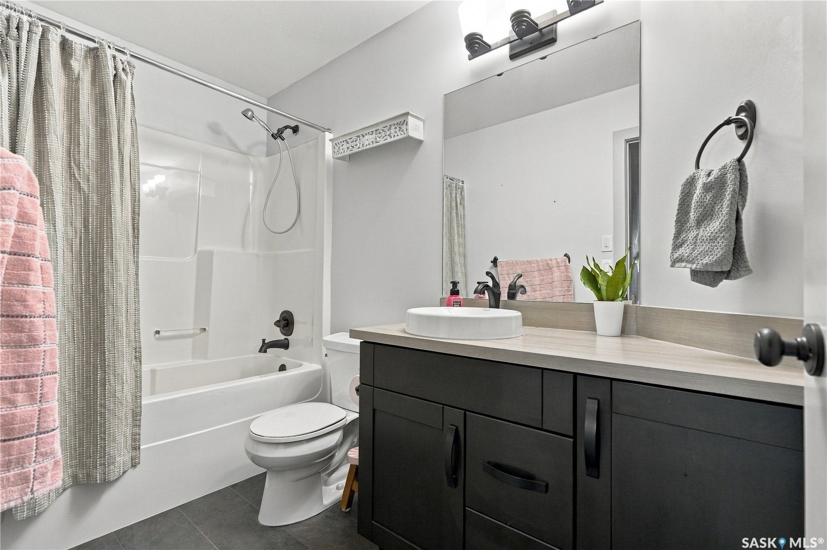 Modern 2nd floor bathroom vanity with a vessel sink, light-toned countertop, and dark cabinetry