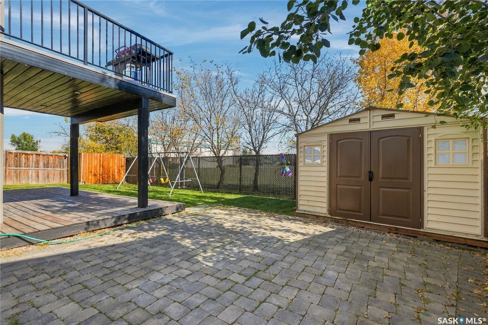 Tiered outdoor spaces featuring a ground-level wood deck and an elevated balcony with black metal railing