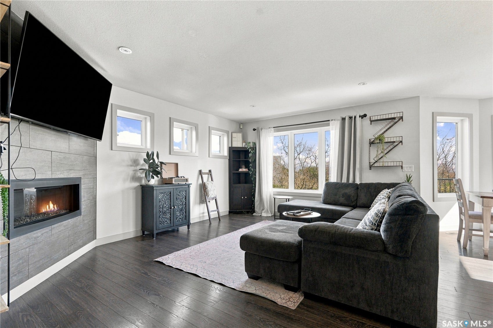 laminate flooring, a gas fireplace with a tile surround, recessed lighting and multiple windows