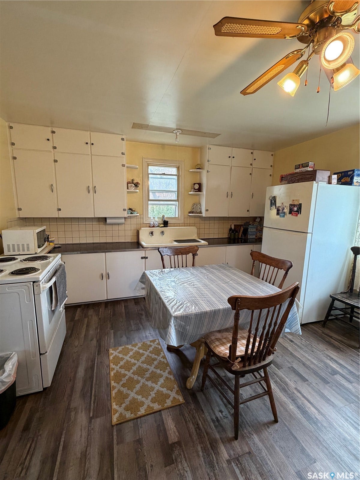 Wood-finish flooring with white cabinetry and a built-in sink, featuring a ceiling fan with integrated lighting