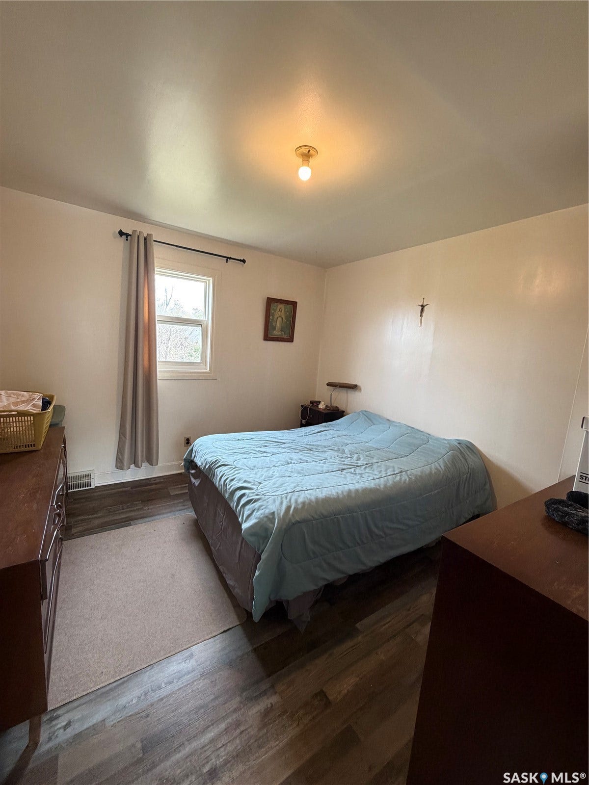 Wood-finish flooring with a window offering natural light, and a ceiling-mounted light fixture