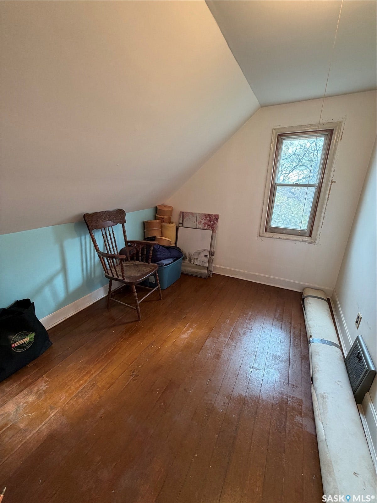 Sloped ceiling room featuring wood-finish flooring and a window