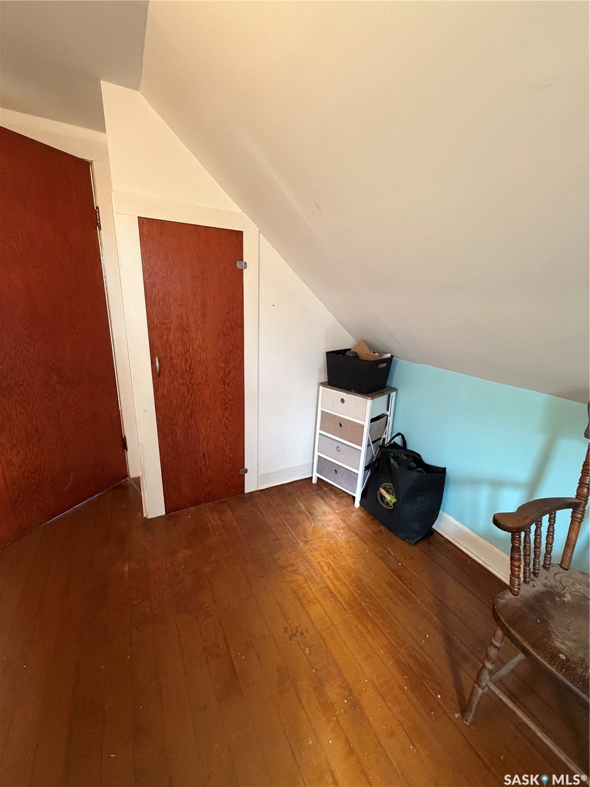 Wood-finish flooring with white trim and a sloped ceiling