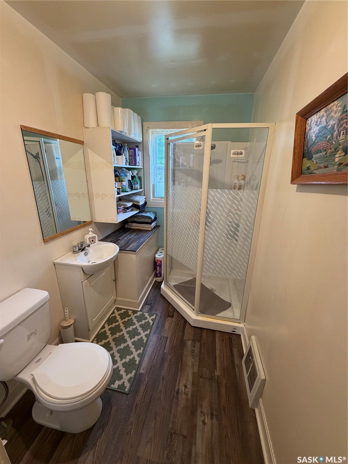 Wood-finish flooring with a corner shower enclosure featuring frosted glass panels