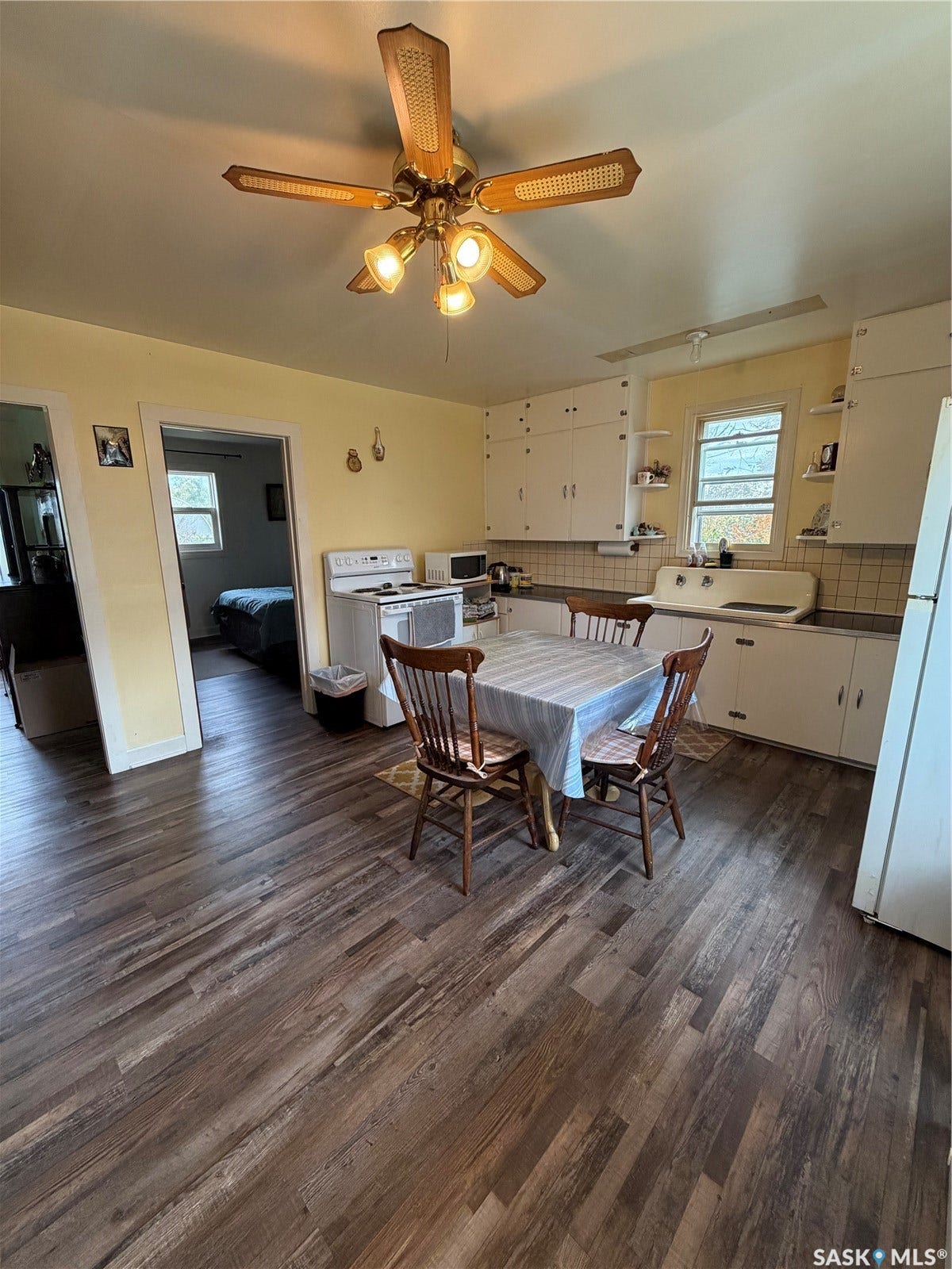 Wood-finish flooring, white cabinetry, integrated sink, and ceiling fan with lighting