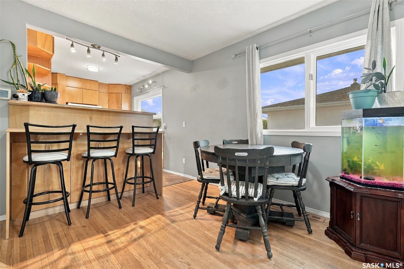 Hardwoodflooring throughout, a kitchen pass-through with a breakfast bar, light wood cabinetry, and a large window