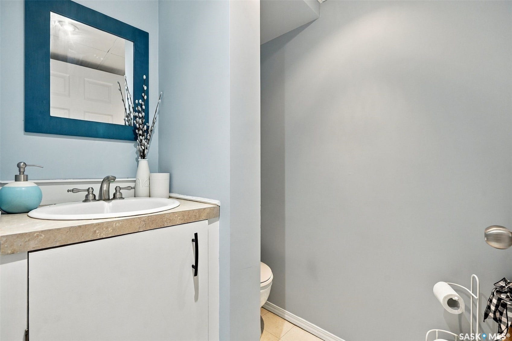 Vanity with an integrated sink, dual-handle faucet, and white cabinetry