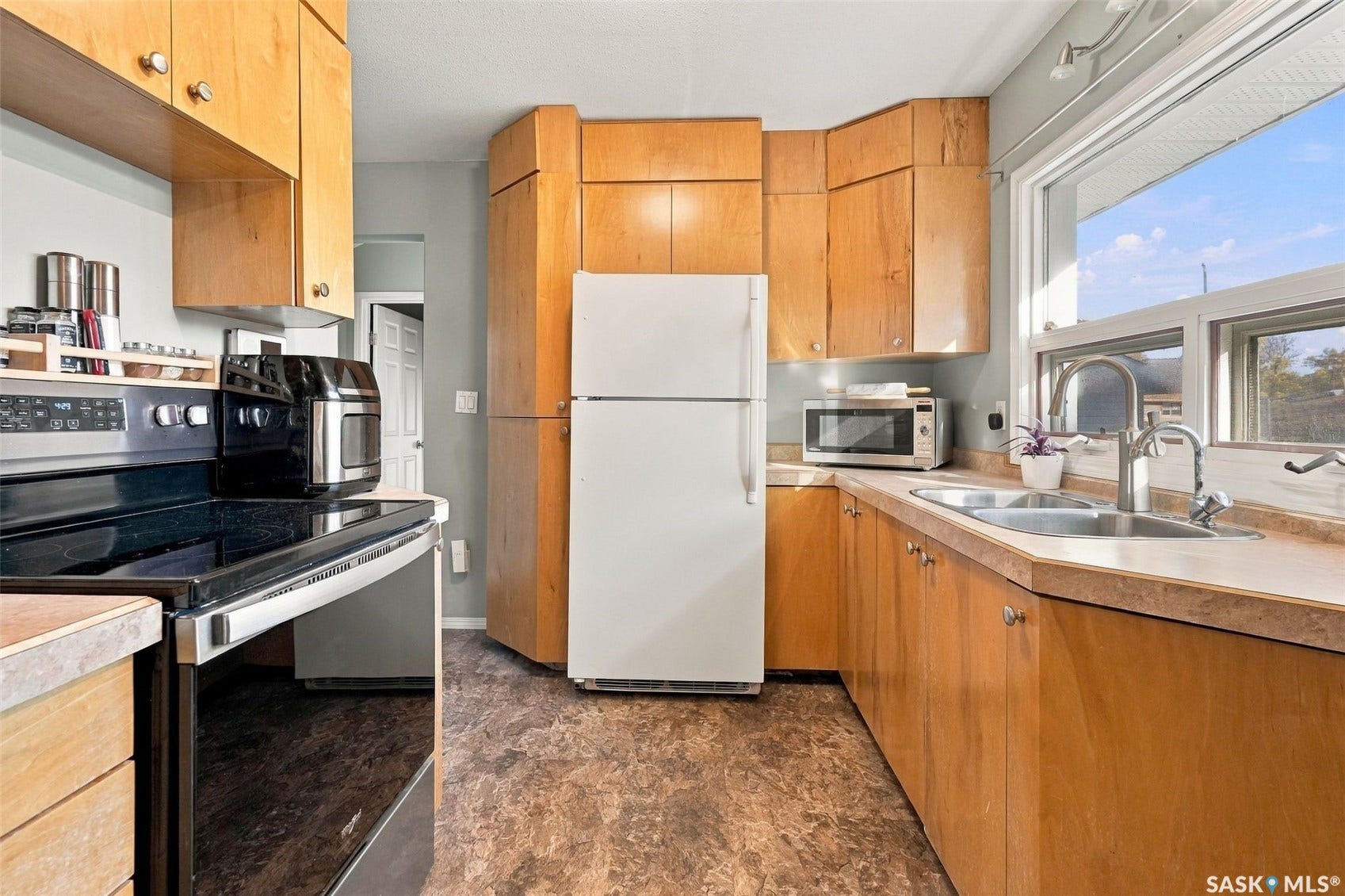 Wood cabinetry with ample storage, stainless steel appliances, and a white refrigerator anchor this galley-style kitchen