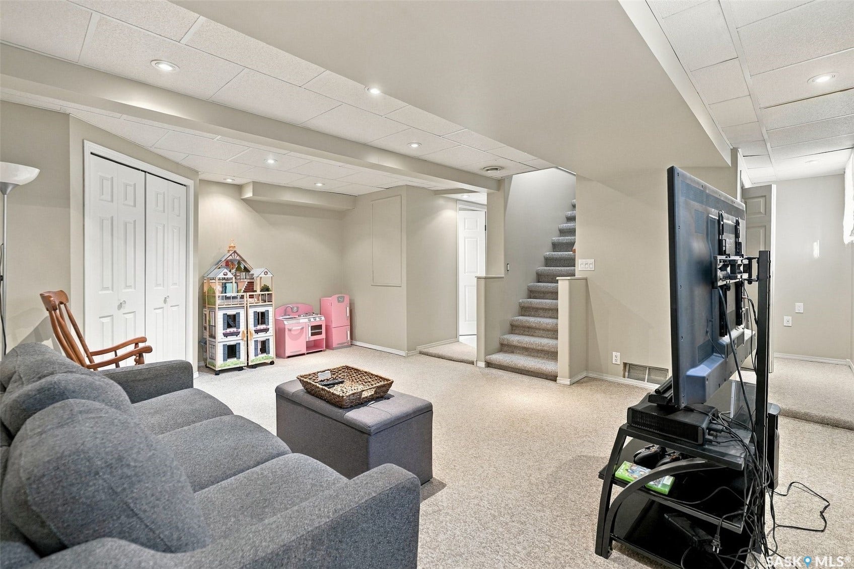 Finished lower level with neutral carpet and recessed lighting, featuring bi-fold closet doors and a carpeted staircase