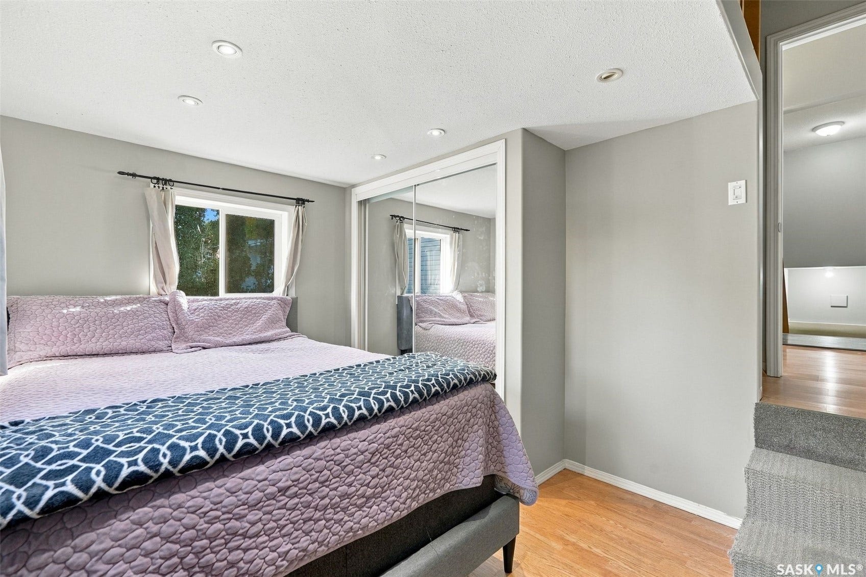 Recessed lighting, wood-finish flooring, and a mirrored closet door