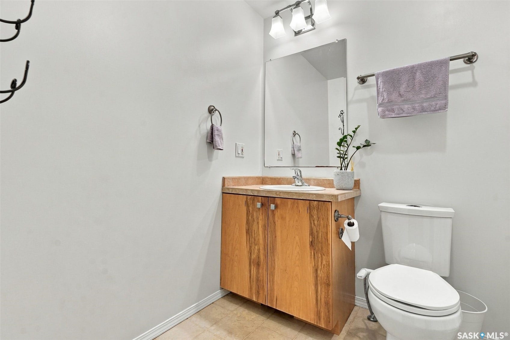 Bathroom featuring a wood vanity with an integrated sink and a light-toned countertop, a wall-mounted mirror, and a modern toilet