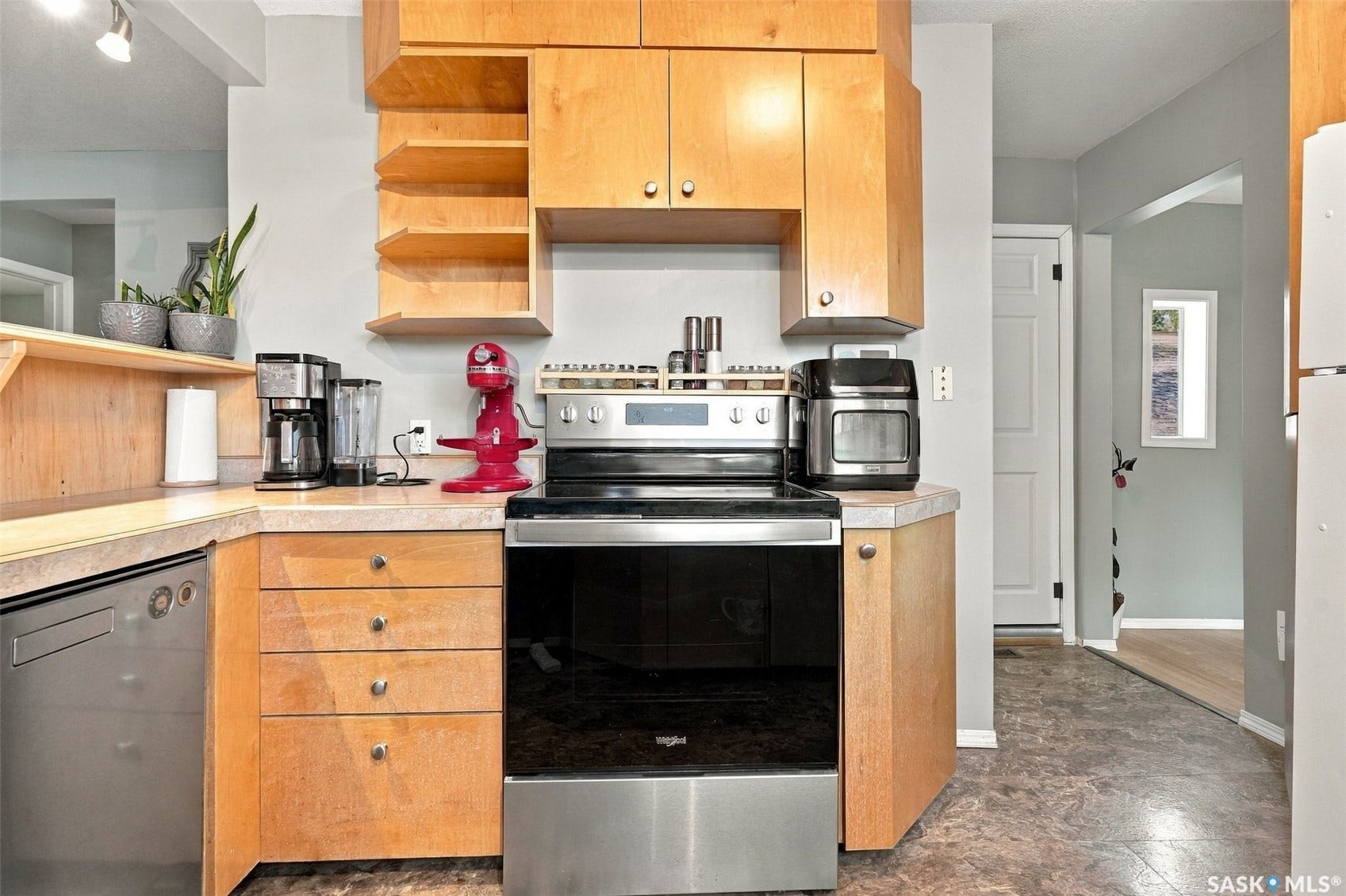 Light wood cabinetry, stainless steel oven, integrated stainless steel dishwasher, and a light-toned countertop