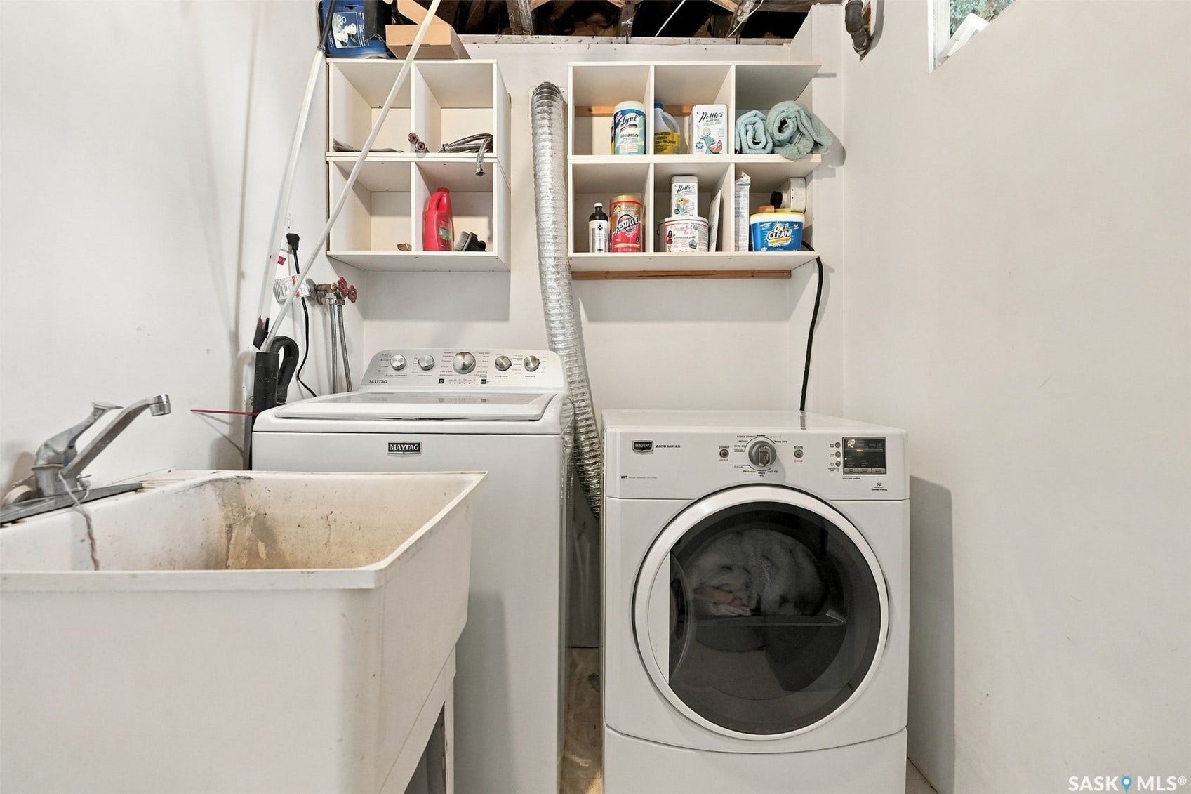 Laundry area featuring a utility sink, washing machine, dryer, and wall-mounted shelving