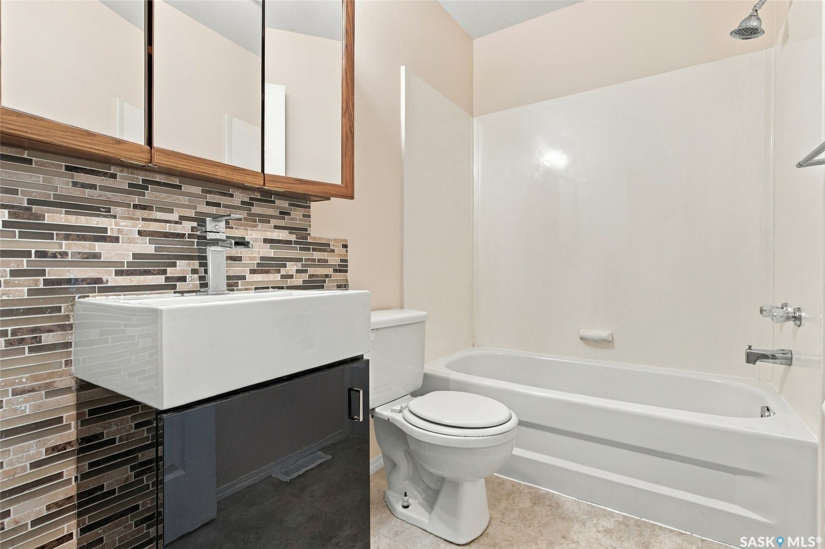 Modern floating vanity with a rectangular vessel sink, mosaic tile backsplash, and a built-in shower/tub combination