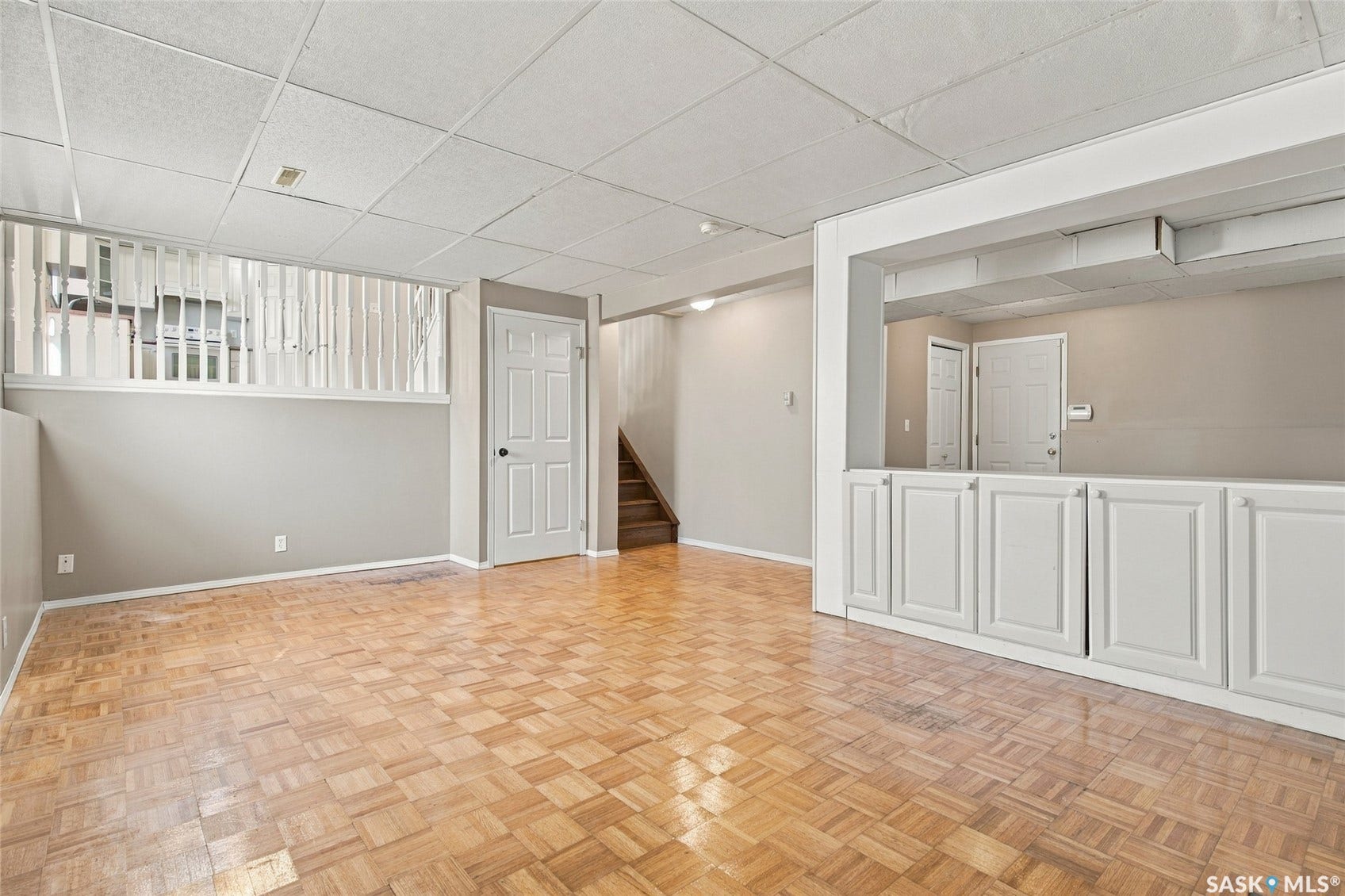 Parquet wood-finish flooring, drop ceiling, built-in white cabinetry, and white paneled doors