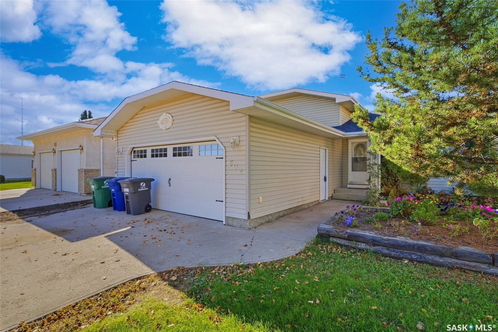 Attached single-car garage with overhead door windows, concrete driveway, and front entry with steps