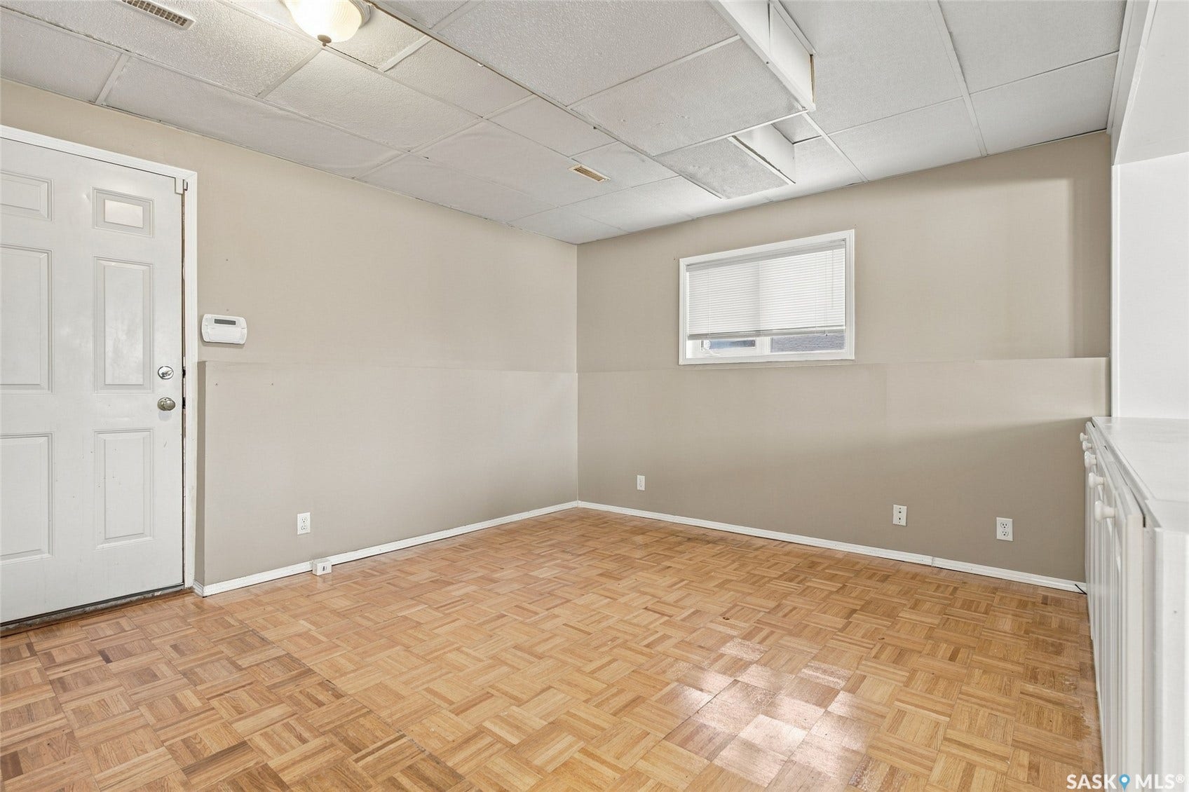 Wood-finish parquet flooring, white trim, and a window with blinds