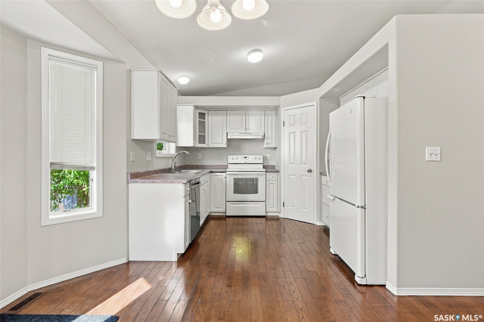 Kitchen featuring wood-finish flooring, white cabinetry, a built-in dishwasher, and recessed lighting