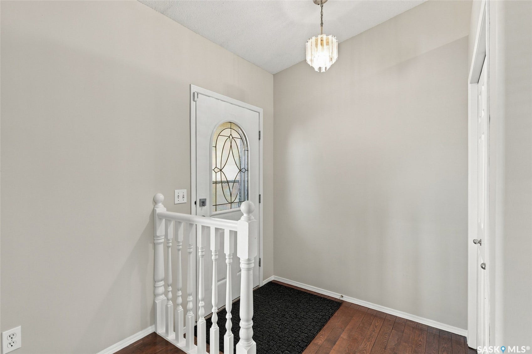 Entryway featuring a decorative glass panel door, wood-finish flooring, and a white baluster railing