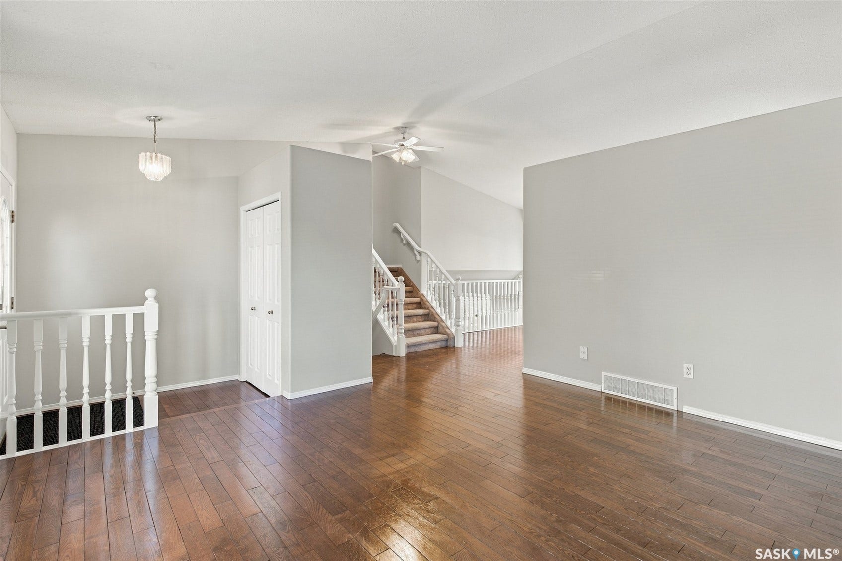Spacious open-concept loft featuring rich wood-finish flooring throughout, soaring ceilings with ceiling fan, and abundant natural light from multiple windows